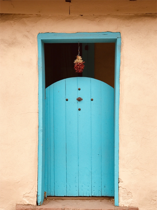 turquoise wood door under red chile ristra